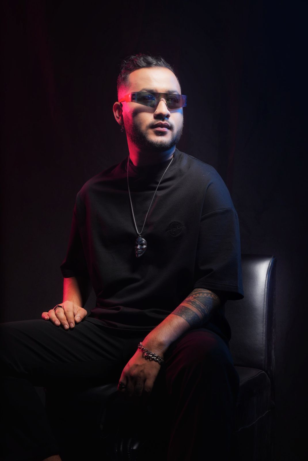 DJ Nihan seated studio portrait under red light