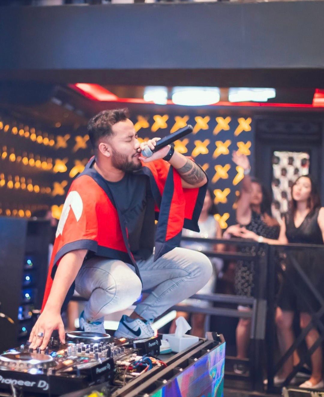 DJ Nihan on the DJ booth with a mic, crowd behind