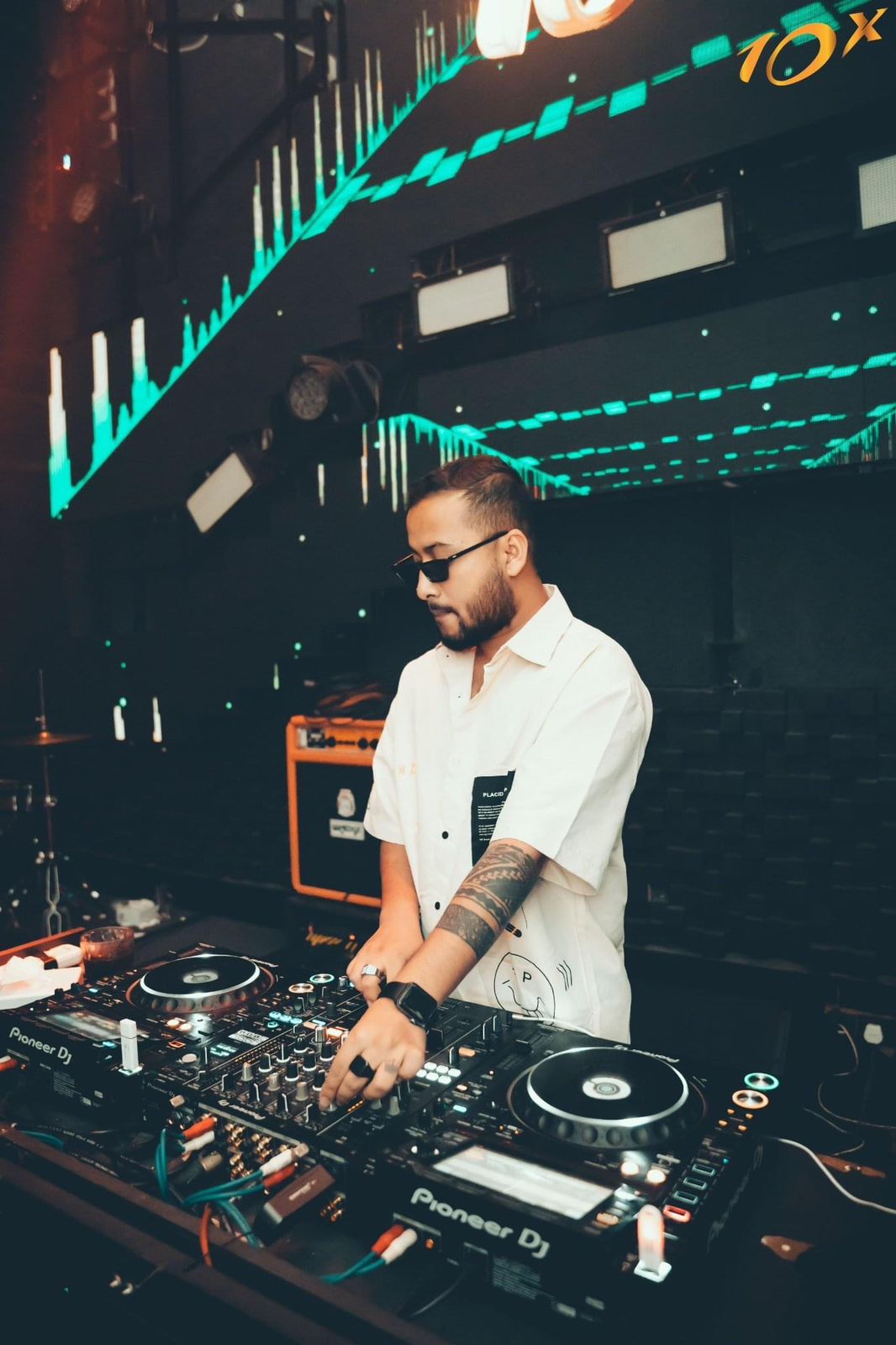 DJ Nihan at the decks against a teal equaliser wall