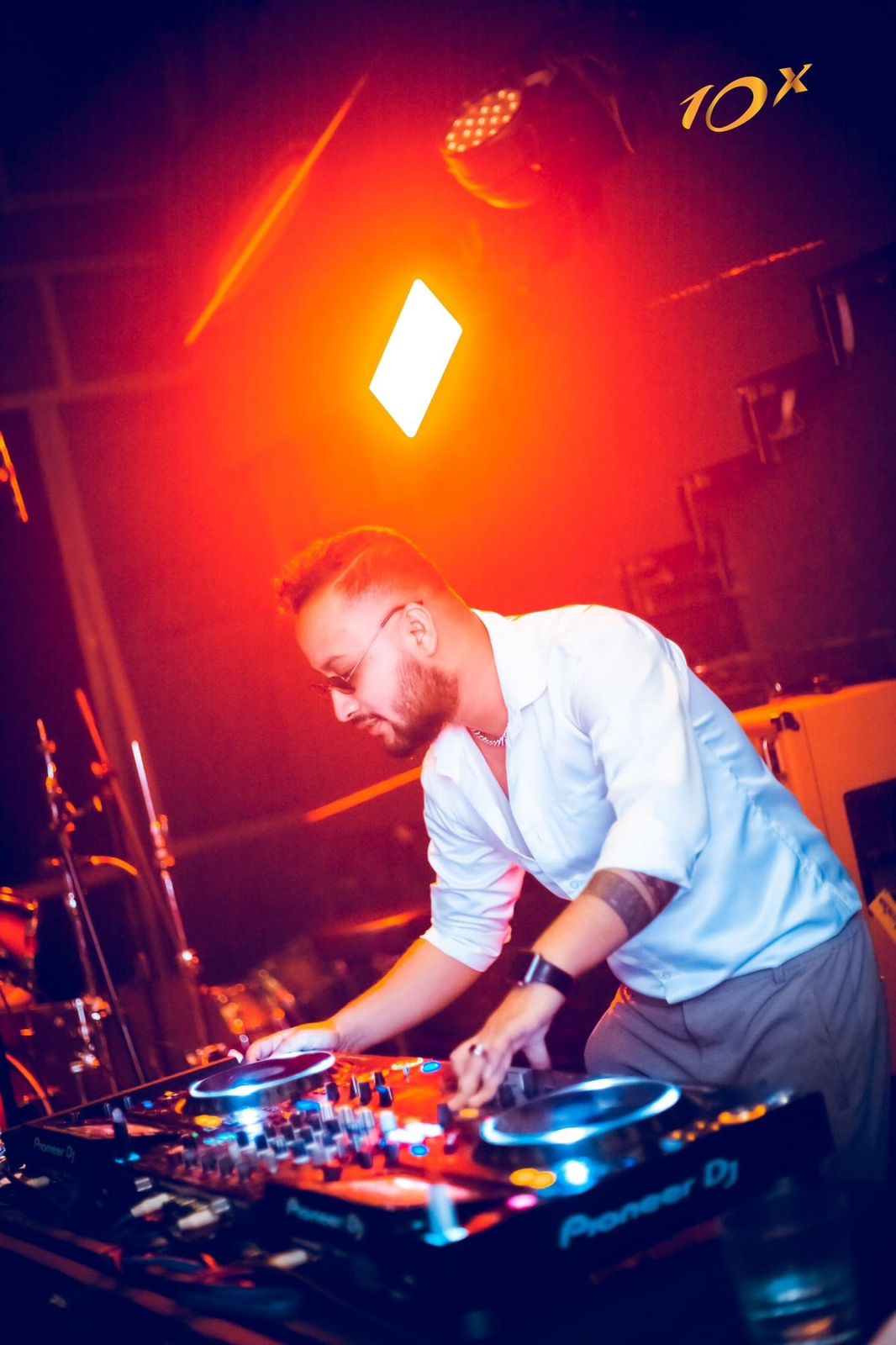 DJ Nihan at the decks in a white shirt under red light