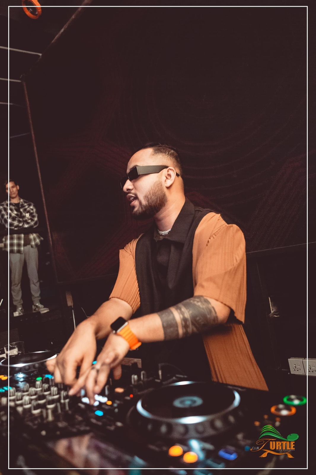 DJ Nihan at the decks in an orange top at Club Turtle